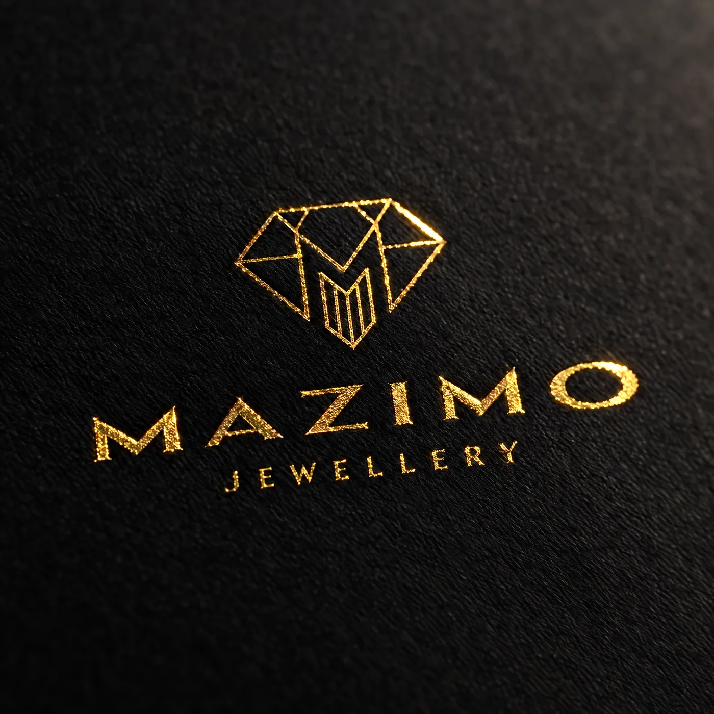 The gold-foil Mazimo Jewellery logo, a diamond mark above the name, pressed into matte black paper
