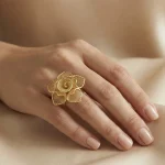 21K gold flower design ring with textured details on a model hand and white background